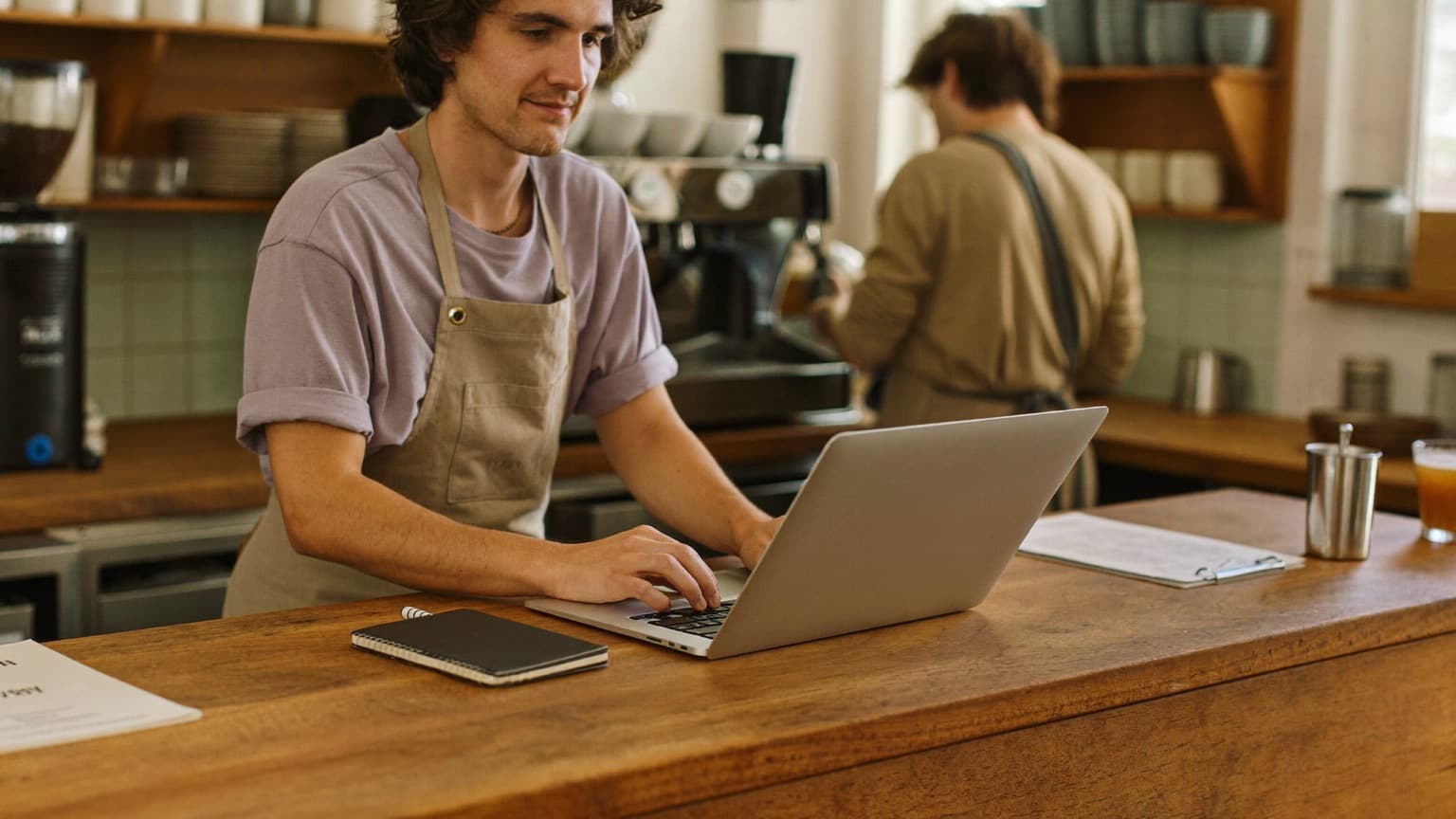 Un gérant de café prépare le planning en ligne de son équipe derrière le comptoir